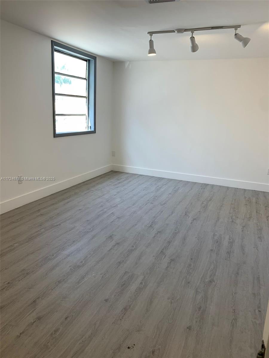 An empty room features light gray wood-look flooring, white walls, and a multi-pane window — 638 NW 62nd St, Miami FL 33150, MIAMI, FL