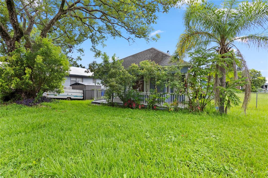 A small house with a front porch sits in a large, grassy yard with trees — 1418 MASSACHUSSETTS AVENUE, ST CLOUD, FL