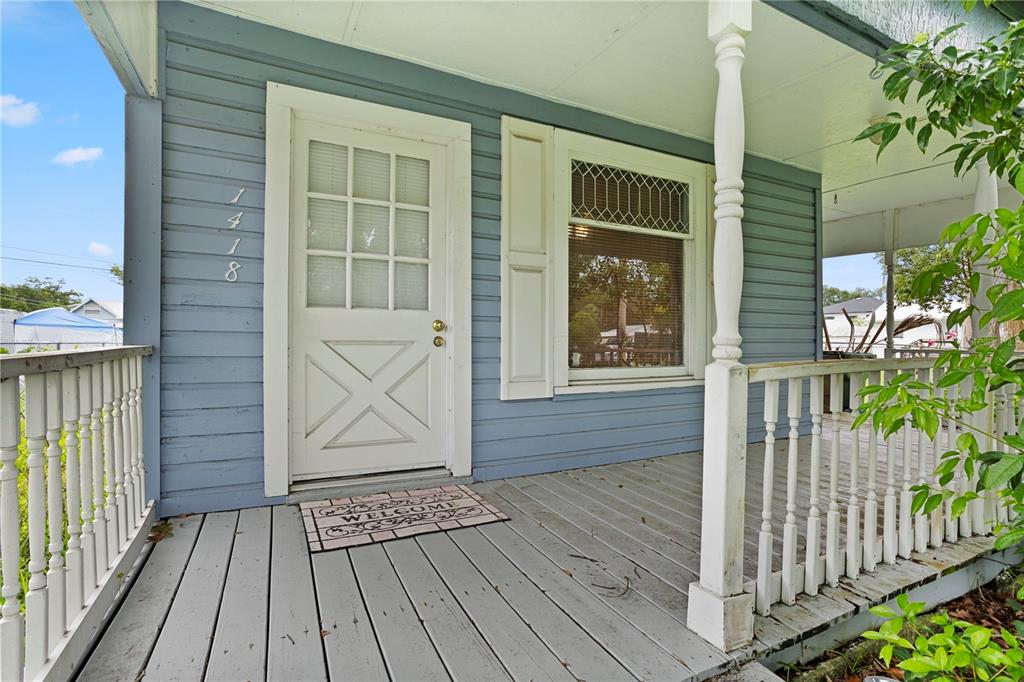 A blue-sided house features a front porch with a white railing and a welcome mat — 1418 MASSACHUSSETTS AVENUE, ST CLOUD, FL