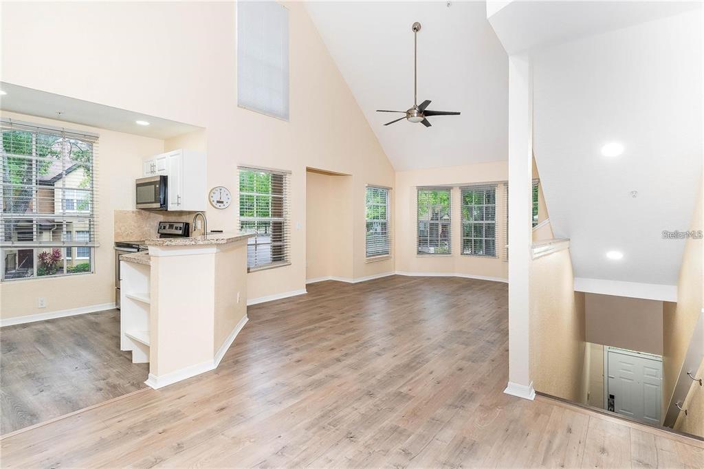 An open-concept living area with vaulted ceilings, wood-look flooring, and an adjacent kitchen — 6308 RALEIGH STREET UNIT 311, ORLANDO, FL