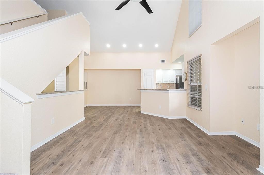 A living area with vaulted ceilings, wood-look flooring, and an open kitchen with a breakfast bar — 6308 RALEIGH STREET UNIT 311, ORLANDO, FL