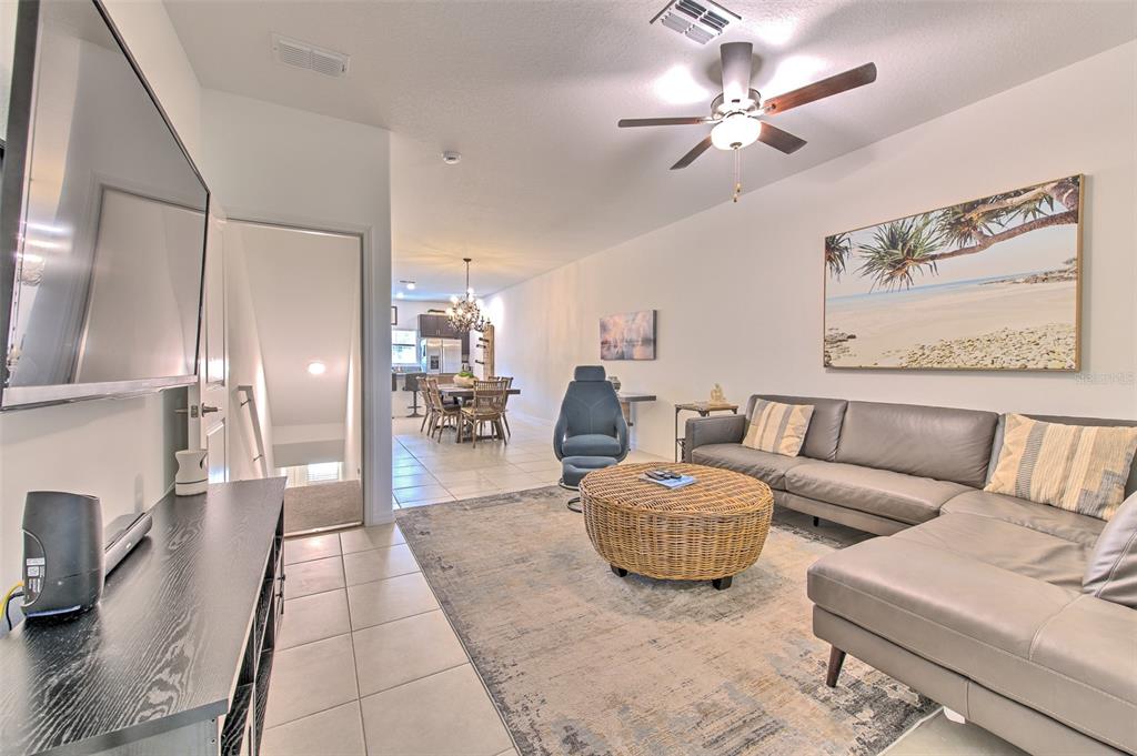 A living room with a grey sectional sofa, wicker coffee table, and adjacent dining area — 4722 TUSCAN LOON DRIVE, TAMPA, FL