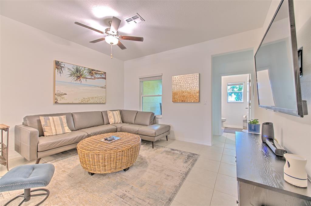 A living room features a grey sectional sofa, a round wicker coffee table, and television — 4722 TUSCAN LOON DRIVE, TAMPA, FL