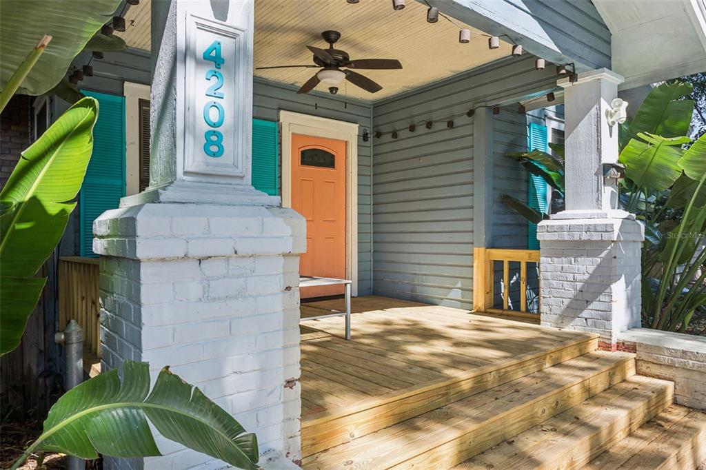 A wooden front porch with white brick columns and an orange door on a house — 4208 N MARGUERITE, TAMPA, FL