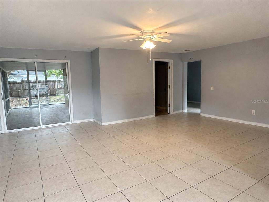 A spacious room with light-colored tile flooring, a ceiling fan, and sliding glass patio doors — 1519 LYNN AVENUE, CLEARWATER, FL