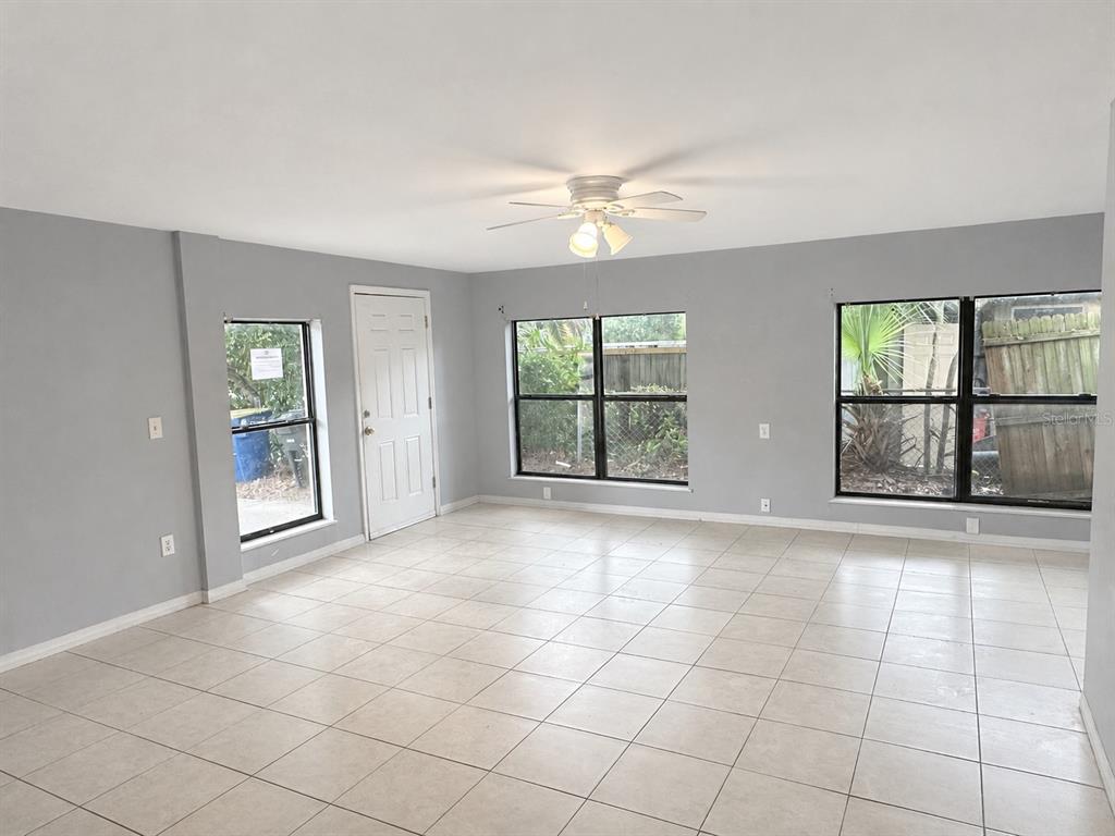 An empty room with light gray walls, tile flooring, a ceiling fan, and three windows — 1519 LYNN AVENUE, CLEARWATER, FL