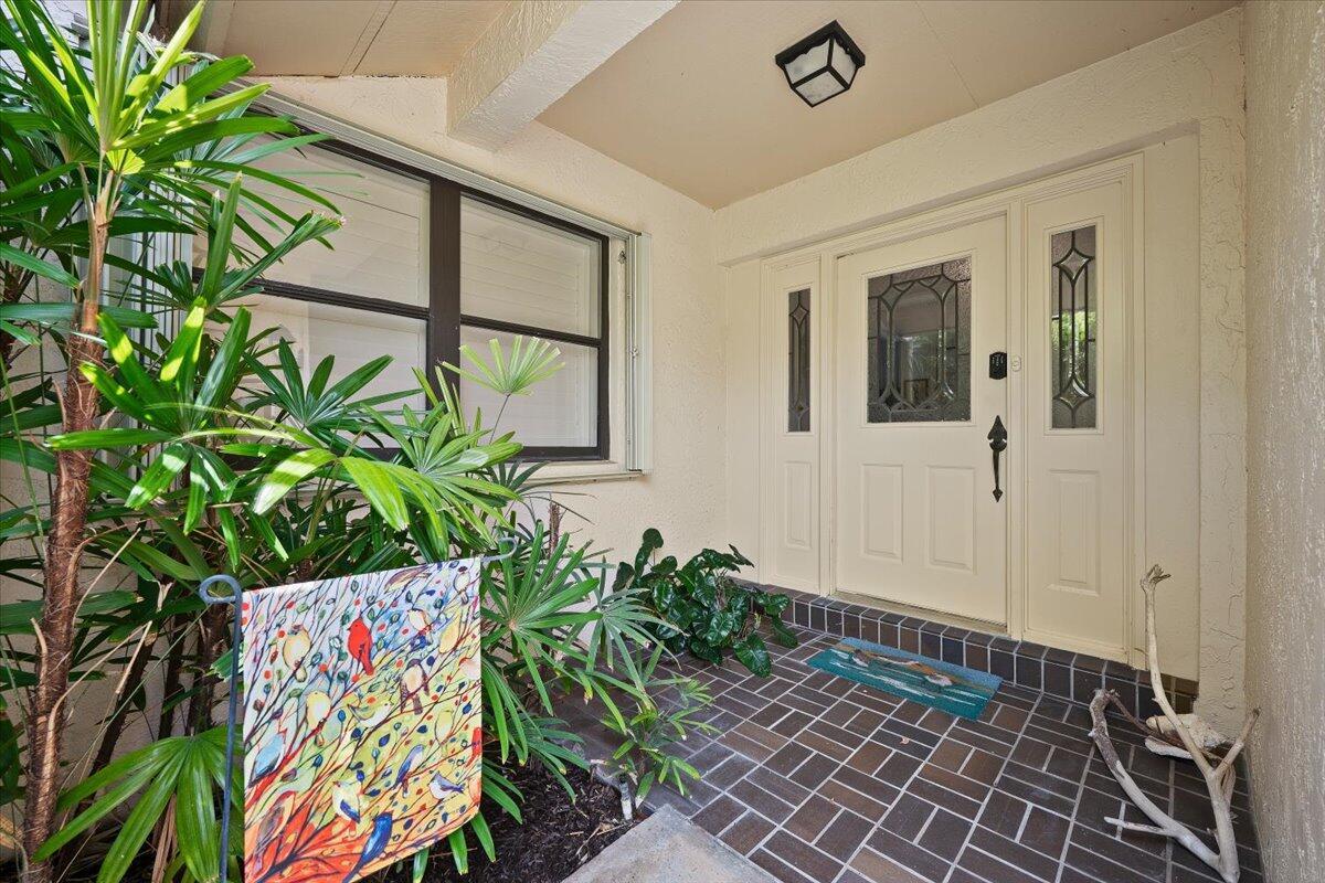 A front entryway features a tiled porch, a white double door, and a nearby plant — 16913 Waterbend Drive # 165, Jupiter FL 33477, JUPITER, FL