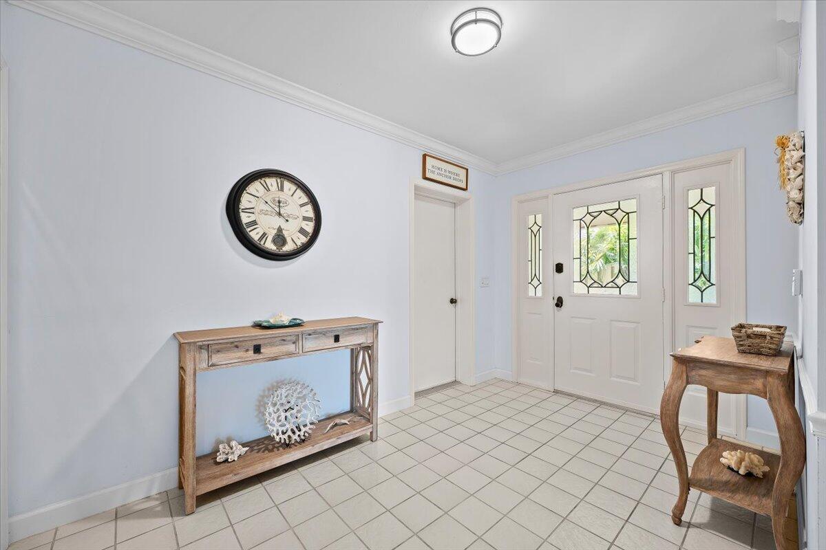 An entryway features light blue walls, tile flooring, a wooden console table, and a front door — 16913 Waterbend Drive # 165, Jupiter FL 33477, JUPITER, FL