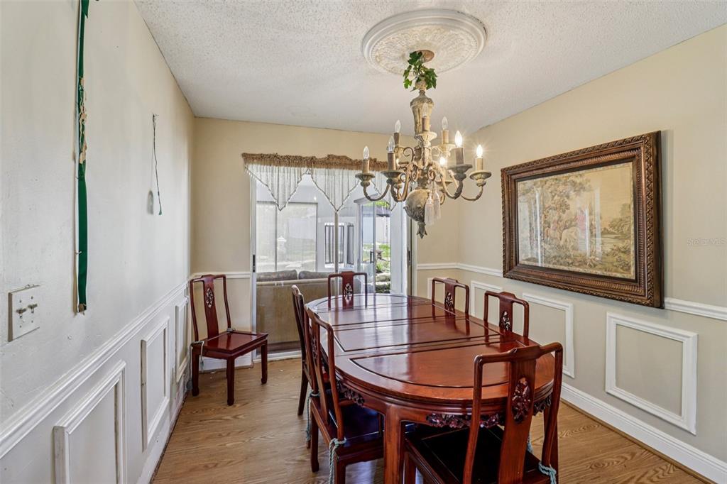 A dining room features a wooden table, chairs, a chandelier, and wainscoting on the walls — 684 REILLYS ROAD, PORT ORANGE, FL