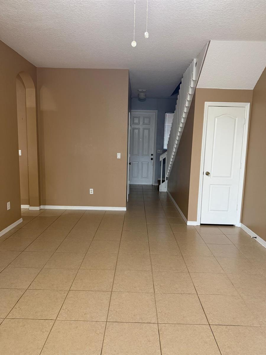An entryway with tan tile flooring, a white staircase, and a closed door — 1510 Seminole Palms Drive, FL 33463, FL