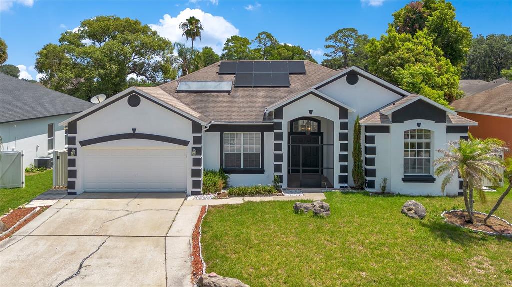 A single-story house with a white exterior, black trim, solar panels, and a two-car garage — 216 BOXWOOD DRIVE, DAVENPORT, FL