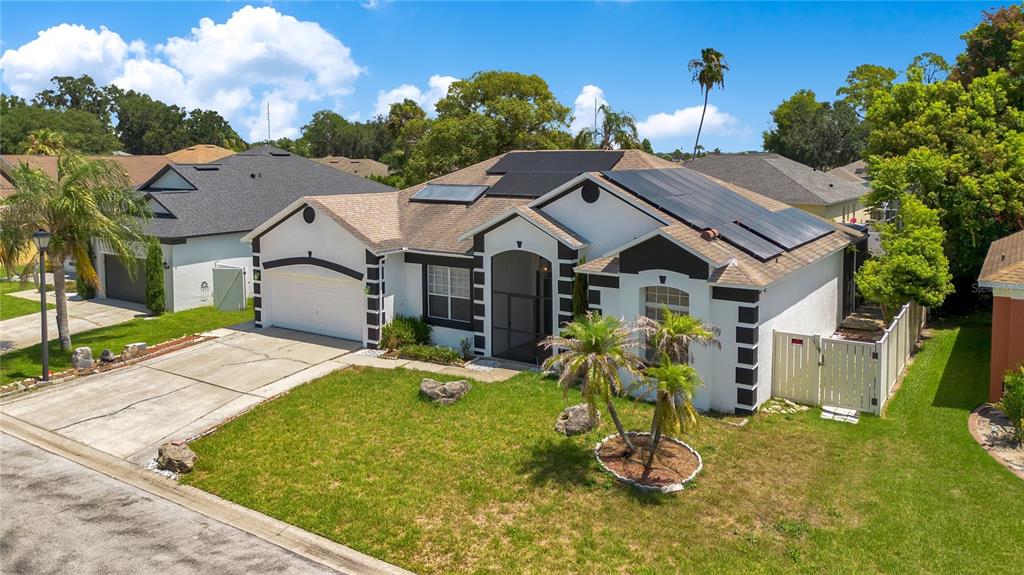 An exterior view of a single-story house with solar panels on the roof — 216 BOXWOOD DRIVE, DAVENPORT, FL