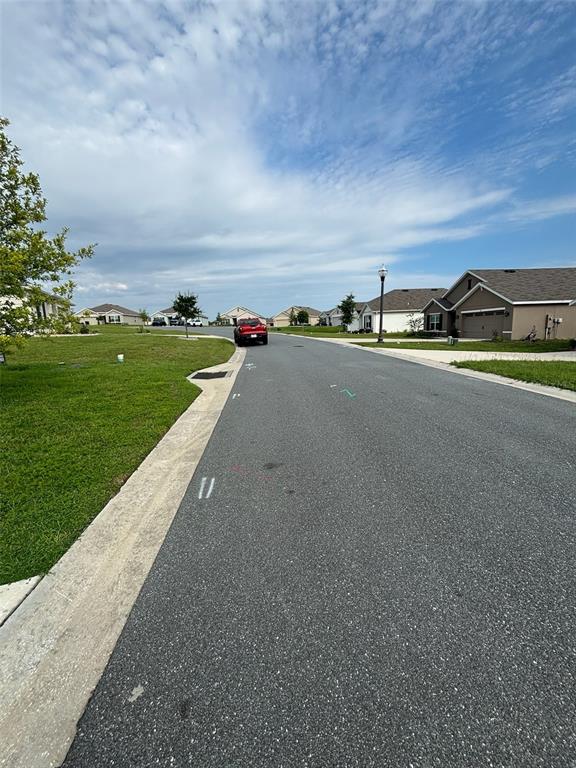 A residential street features asphalt pavement, concrete curbs, and single-family homes under a cloudy sky — 361 W FAIRWAYS VIEW DRIVE, BEVERLY HILLS, FL