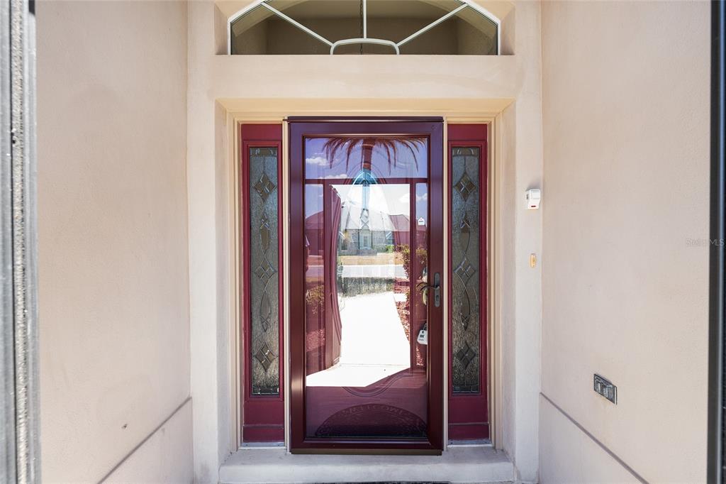 A front entryway features a red storm door with glass panels and sidelights — 2033 SALMON WAY, THE VILLAGES, FL