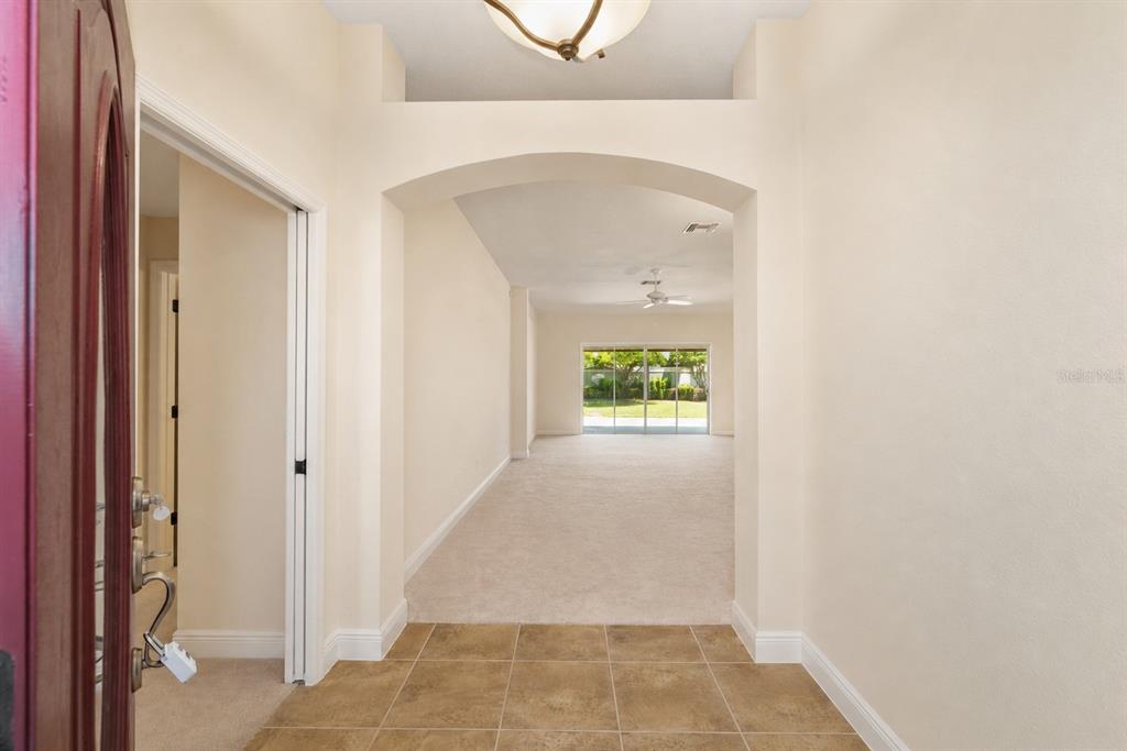 An entryway with tiled flooring leads into a carpeted living area with sliding glass doors — 2033 SALMON WAY, THE VILLAGES, FL