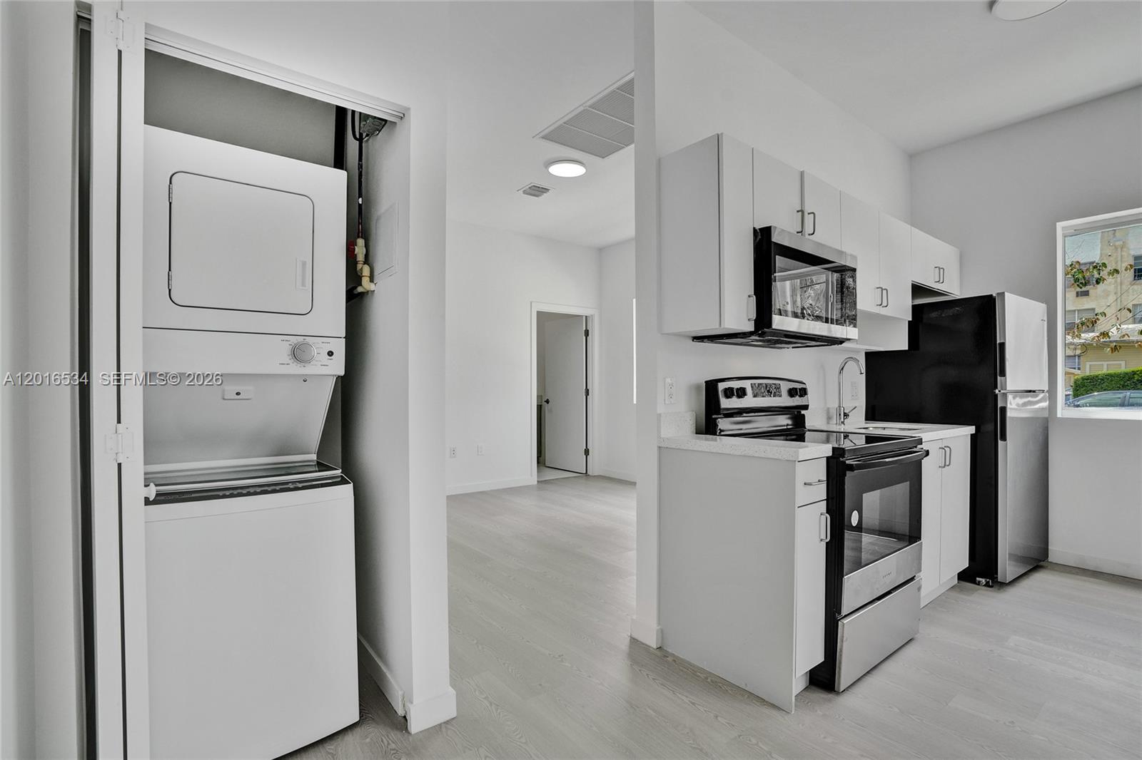 A kitchen with stainless steel appliances and a stacked washer-dryer unit in a closet — 1567 NW 1st St # 1, Miami FL 33125, MIAMI, FL