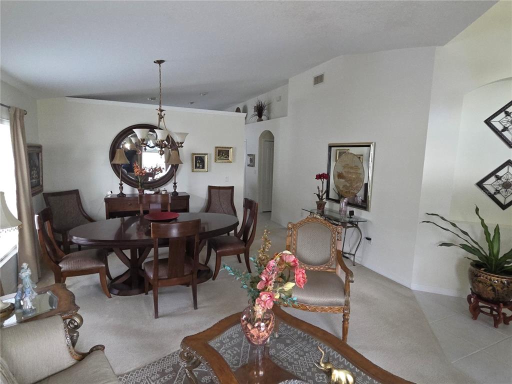 A dining area and living space feature carpeted floors, a wooden table, and decorative wall art — 3849 ROLLINGSFORD CIRCLE, LAKELAND, FL
