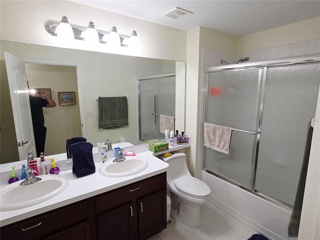 A bathroom features a double vanity with dark cabinets, a mirror, and a shower-tub combo — 3849 ROLLINGSFORD CIRCLE, LAKELAND, FL