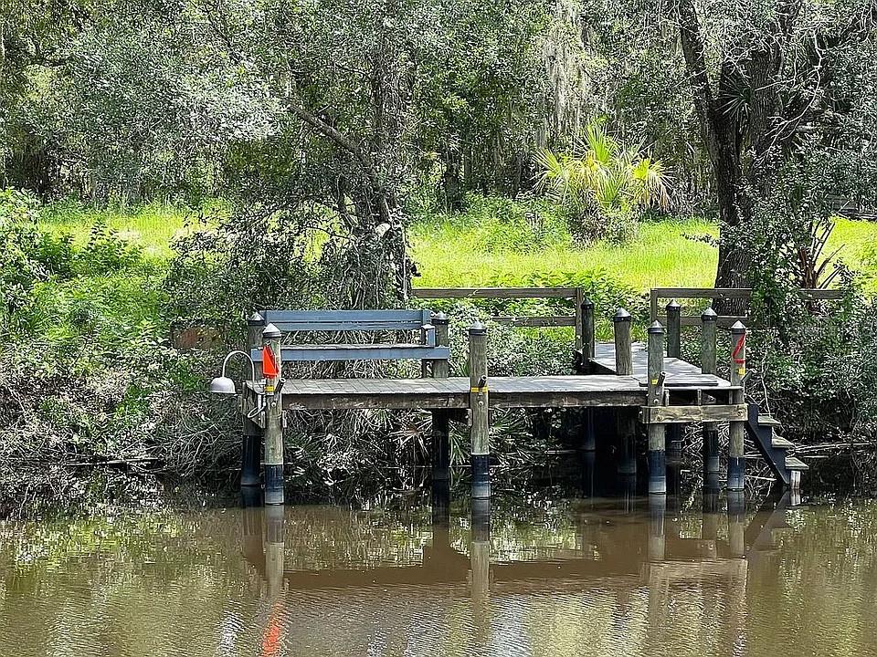 A wooden dock with a bench sits along a calm, dark-water canal surrounded by trees — 27354 SAN CARLOS DRIVE, PUNTA GORDA, FL