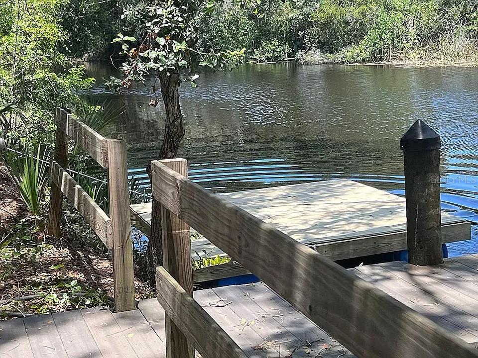 A wooden dock with a railing extends over a calm body of water — 27354 SAN CARLOS DRIVE, PUNTA GORDA, FL