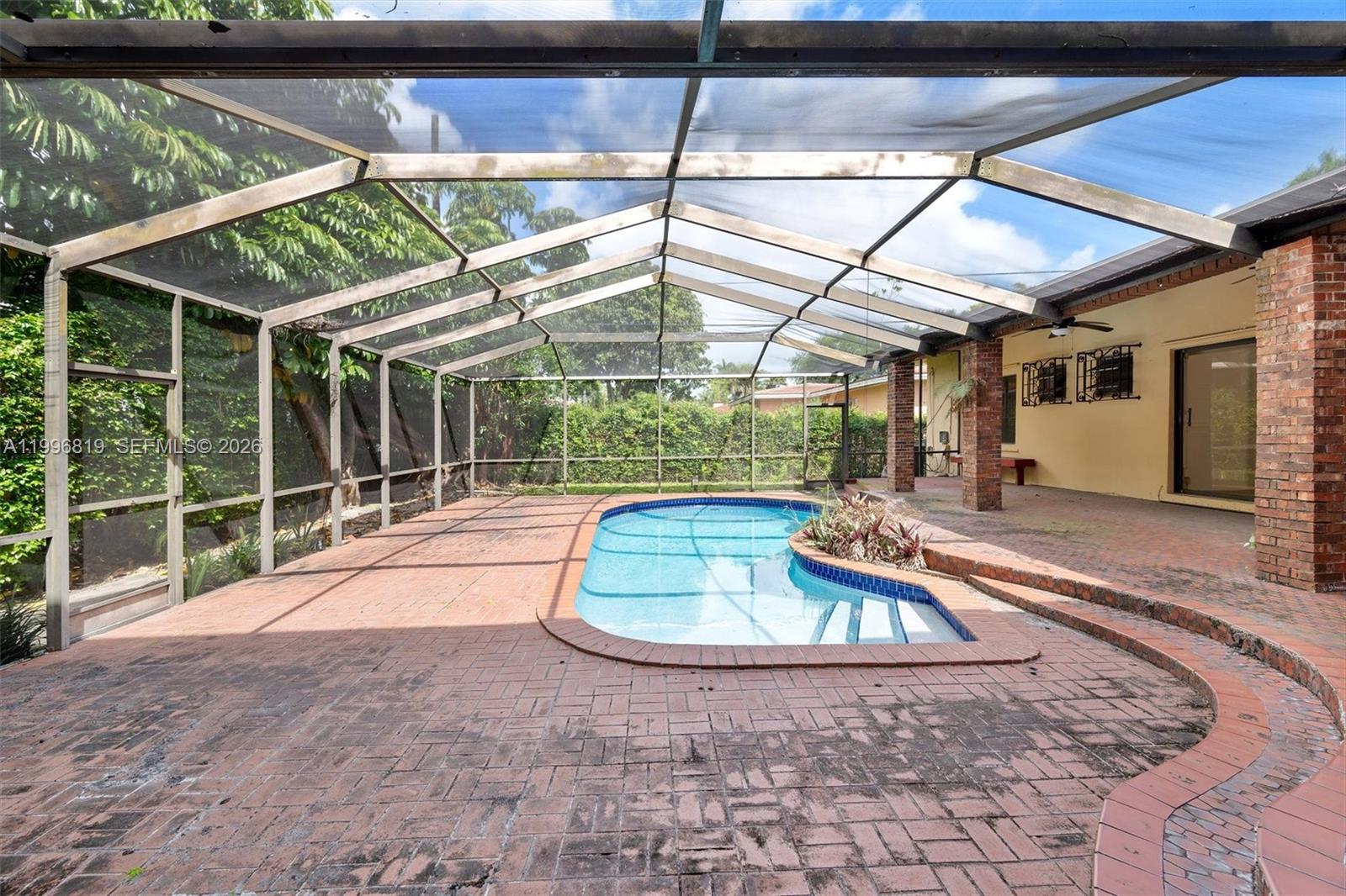 A screened-in patio features a brick deck surrounding an in-ground swimming pool — 1545 Cantoria Ave, Coral Gables FL 33146, CORAL GABLES, FL