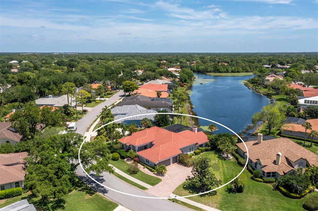 An aerial view shows a single-story house with a red tile roof near a lake — 8615 WOODBRIAR DRIVE, SARASOTA, FL
