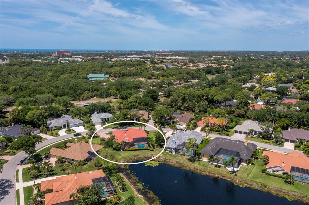 An aerial view shows a house with a red roof and pool near a pond — 8615 WOODBRIAR DRIVE, SARASOTA, FL