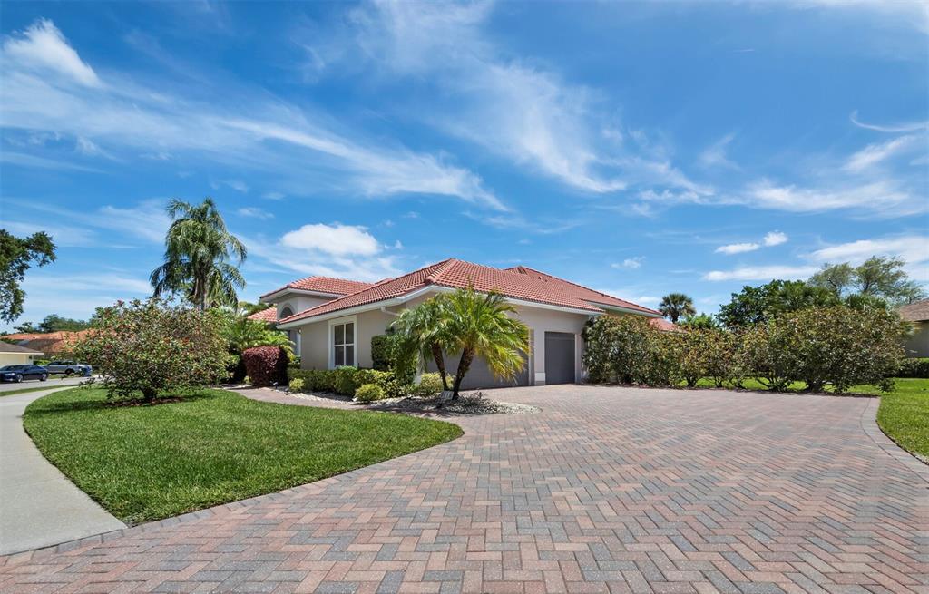 A single-story house with a red tile roof and a large brick paver driveway — 8615 WOODBRIAR DRIVE, SARASOTA, FL
