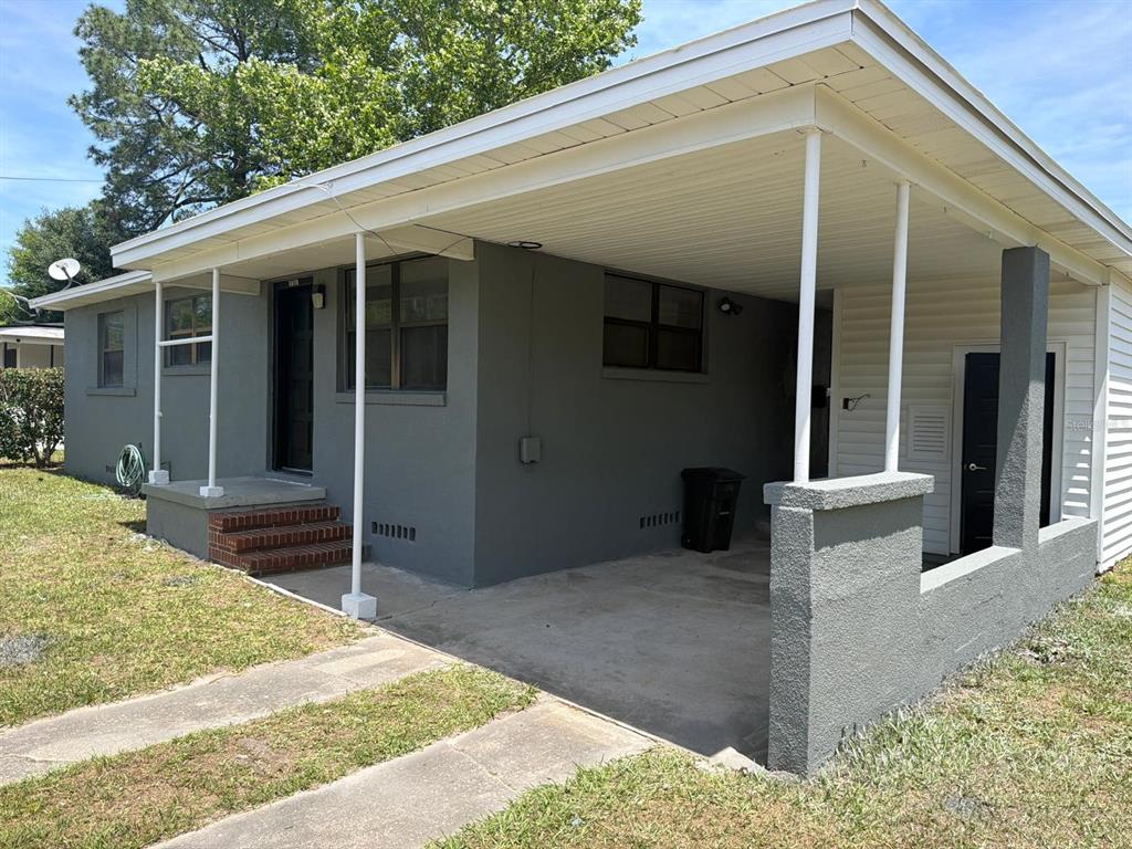 A gray house features a covered carport, a concrete driveway, and brick steps at the entrance — 3761 JAMMES ROAD, JACKSONVILLE, FL