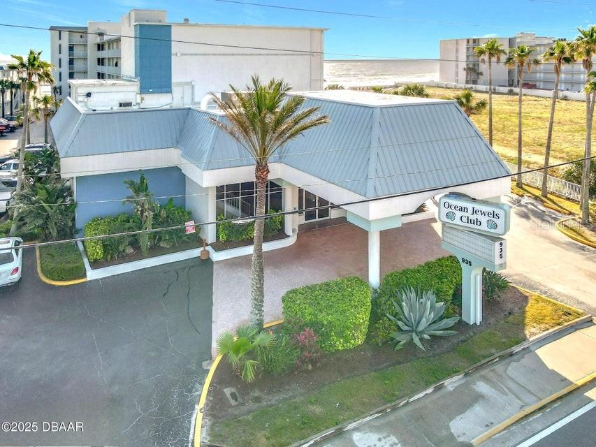 An aerial view shows the exterior of a blue building with a covered entrance — 935 S ATLANTIC AVENUE UNIT 355, DAYTONA BEACH, FL