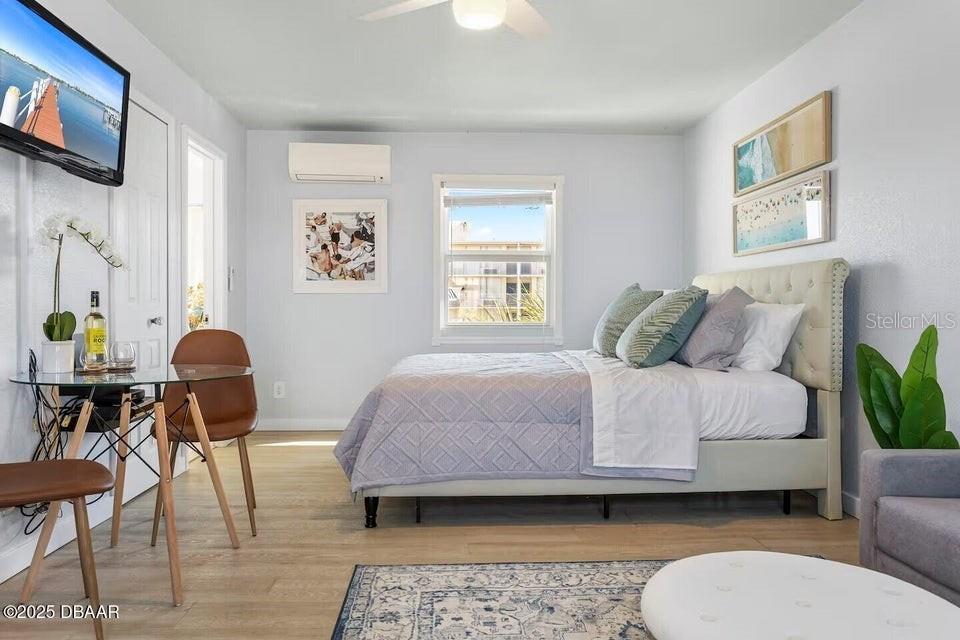 A bedroom features a bed, a small dining table, and a wall-mounted television — 935 S ATLANTIC AVENUE UNIT 355, DAYTONA BEACH, FL