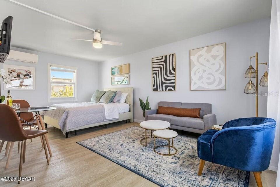 A studio apartment features a bed, a gray sofa, a blue chair, and a dining table — 935 S ATLANTIC AVENUE UNIT 355, DAYTONA BEACH, FL