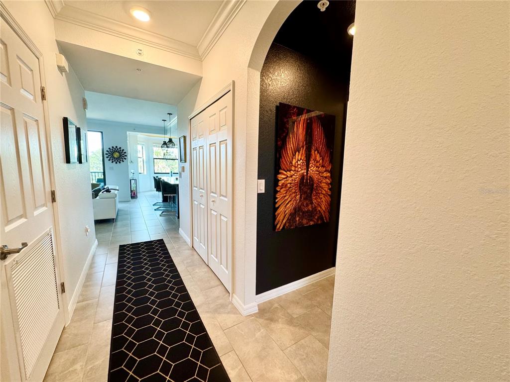 A hallway with tile flooring leads toward a kitchen area past a black accent wall — 18028 GAWTHROP DRIVE UNIT 303, BRADENTON, FL