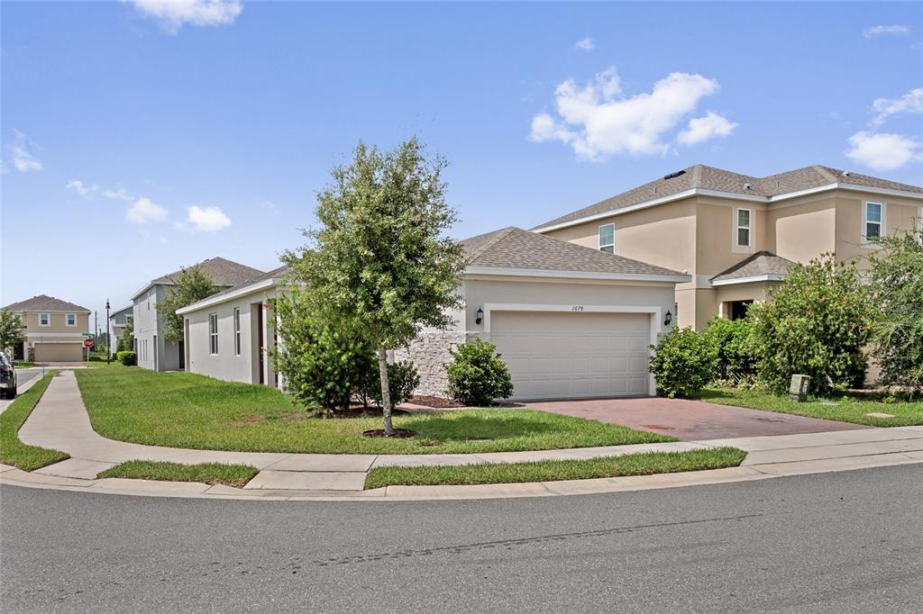 A single-story suburban house with a two-car garage and a stone-accented exterior — 1678 SWAN SWIM DRIVE, DAVENPORT, FL
