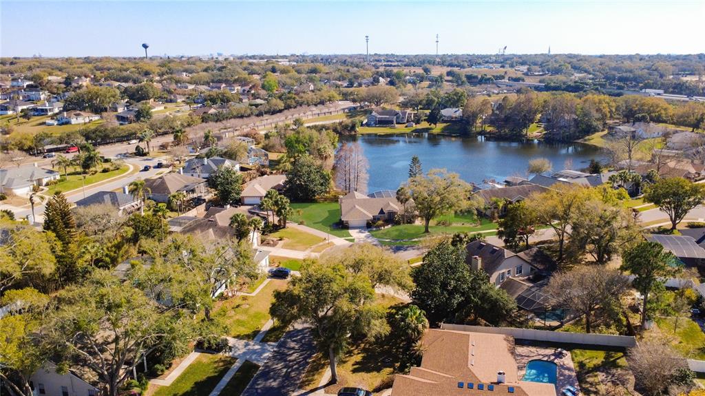 An aerial view shows a suburban neighborhood with houses surrounding a central lake — 1125 ALMOND TREE CIRCLE, ORLANDO, FL