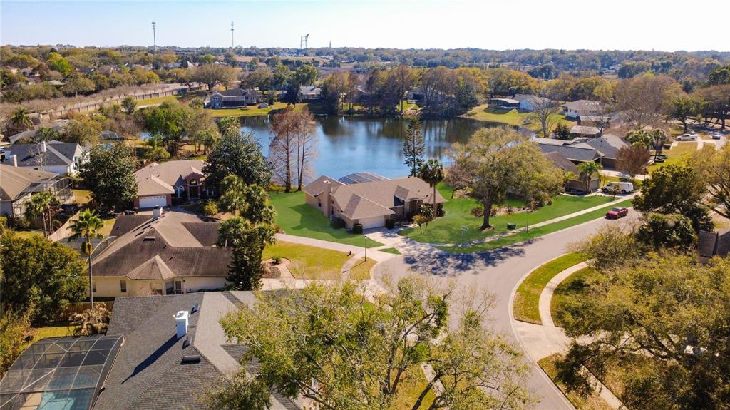 An aerial view shows a suburban neighborhood with houses surrounding a central lake — 1125 ALMOND TREE CIRCLE, ORLANDO, FL