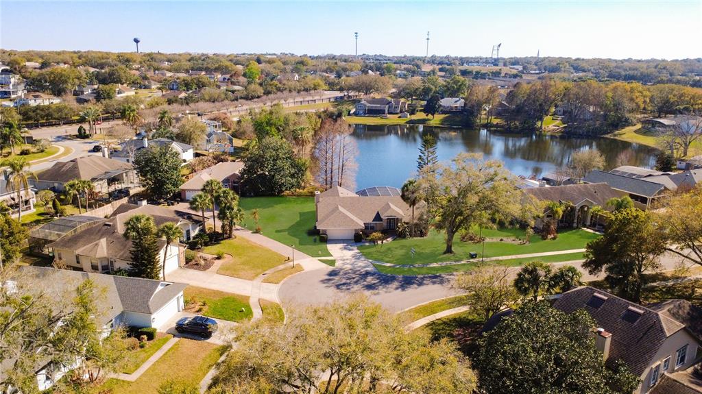 An aerial view shows a suburban neighborhood with houses surrounding a central lake — 1125 ALMOND TREE CIRCLE, ORLANDO, FL