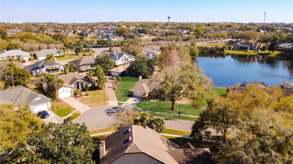 An aerial view shows suburban houses surrounding a lake under a clear blue sky — 1125 ALMOND TREE CIRCLE, ORLANDO, FL