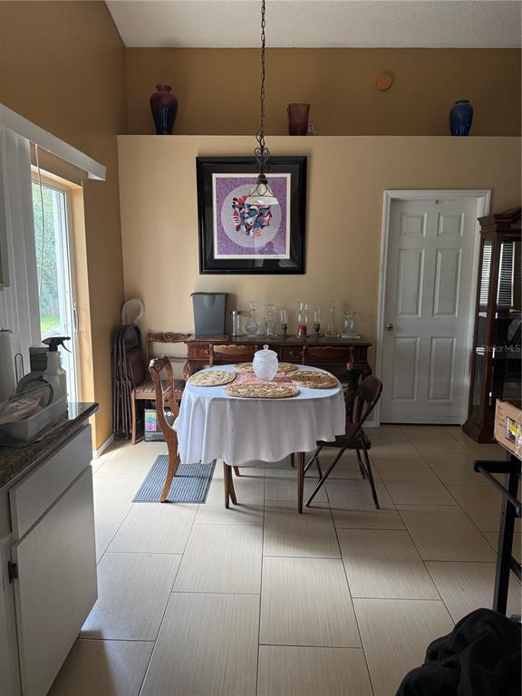 A dining area features a round table with a white cloth, tile flooring, and wall decor — 310 PRINCE STREET, ORLANDO, FL