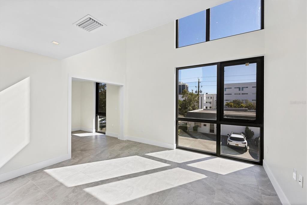 A bright room with high ceilings, large windows, and light-colored tile flooring — 1558 4TH STREET UNIT 216, SARASOTA, FL
