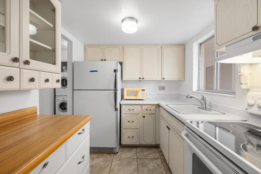 A kitchen features light-colored cabinets, white appliances, a wood-look countertop, and tile flooring — 2326 CANAL DRIVE UNIT G25, BRADENTON, FL