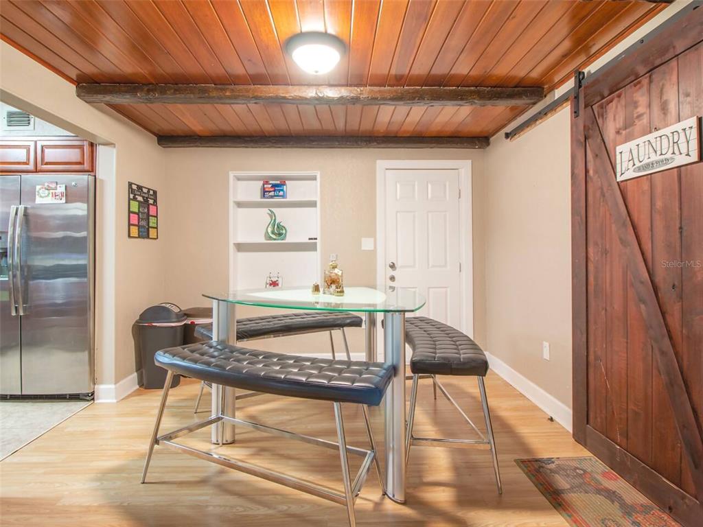 A dining area features a glass table, two black benches, and a wood-paneled ceiling — 1245 CATALPA LANE, ORLANDO, FL