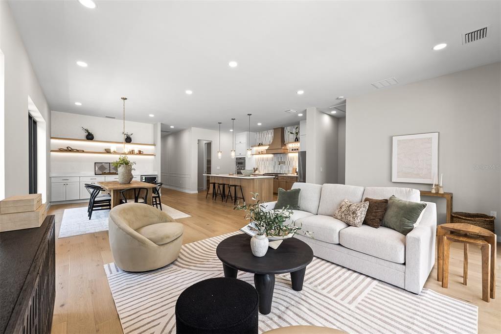 An open-concept living and dining area features light wood floors, a kitchen island, and neutral decor — 106 W KING STREET, ORLANDO, FL