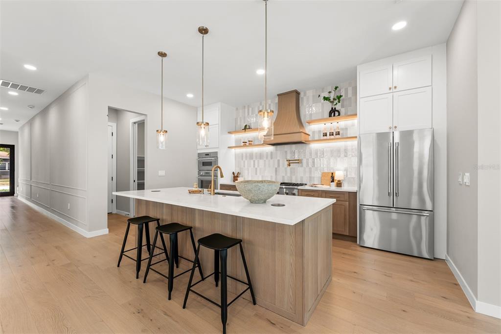A modern kitchen features a wood-toned island with black stools, white cabinetry, and stainless appliances — 106 W KING STREET, ORLANDO, FL