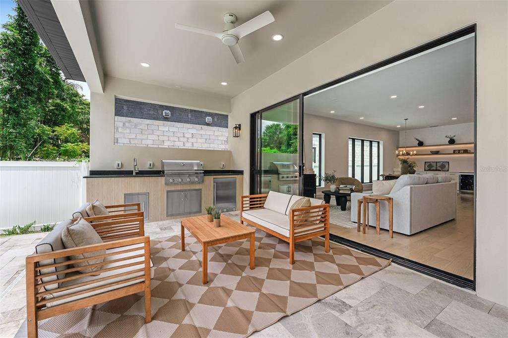 A covered outdoor patio features a built-in grill, seating area, and sliding glass doors — 106 W KING STREET, ORLANDO, FL