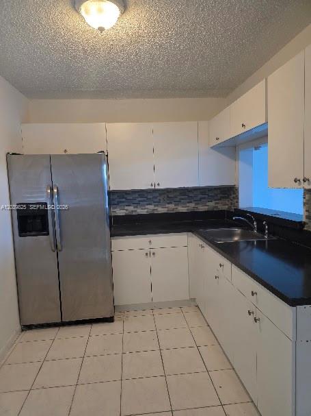 A kitchen with white cabinets, black countertops, a stainless steel refrigerator, and tiled flooring — 8635 NW 8th St # 423, Miami FL 33126, MIAMI, FL
