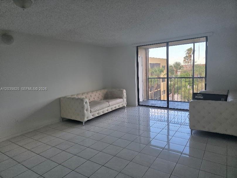 A living room features white tiled floors, a tufted sofa, and a sliding glass door — 8635 NW 8th St # 423, Miami FL 33126, MIAMI, FL