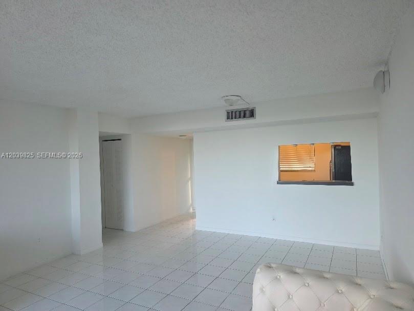 An empty room features white tiled floors, white walls, and a kitchen pass-through window — 8635 NW 8th St # 423, Miami FL 33126, MIAMI, FL
