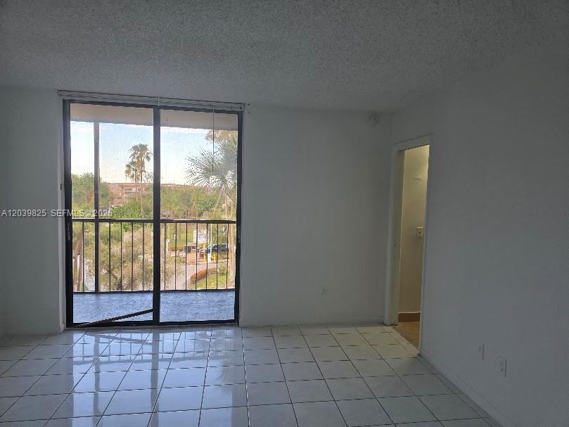 A room with white tile flooring, plain walls, and a sliding glass door to a balcony — 8635 NW 8th St # 423, Miami FL 33126, MIAMI, FL