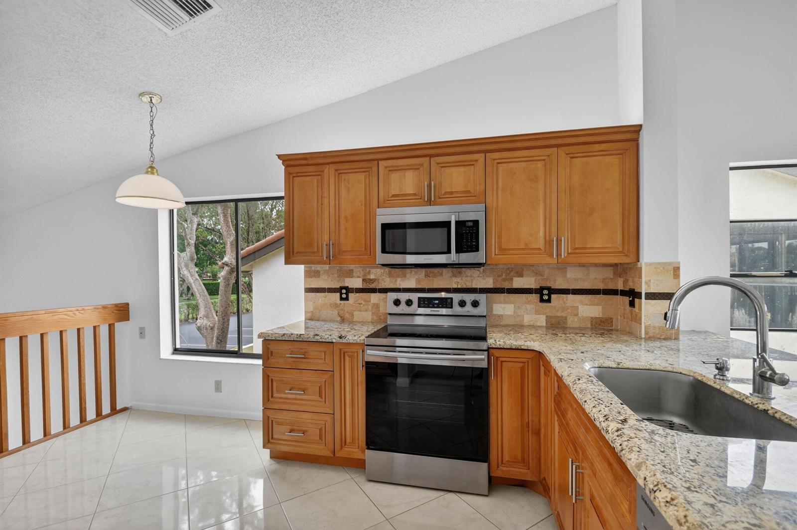 A kitchen features honey-oak cabinets, granite countertops, stainless steel appliances, and a tiled backsplash — 10231 N Circle Lake Drive # 201, Boynton Beach FL 33437, BOYNTON BEACH, FL